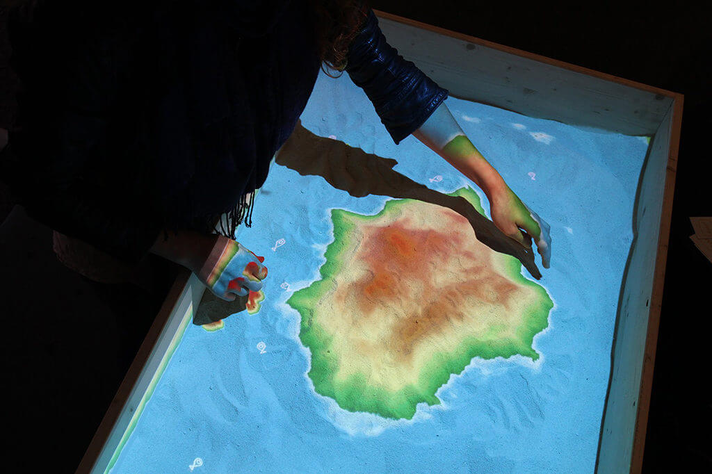 N. Cauvi dessine l'île de La Possession dans le sable de "Géomorphose", œuvre interactive.